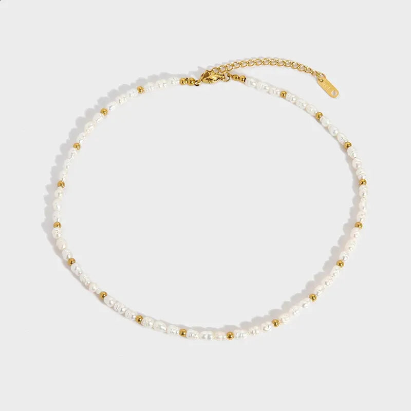 Necklace with white pearls and gold beads on a light gray background