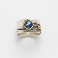 Silver ring with a blue sapphire gemstone, featuring a unique layered design and gold accents, perfect for elegant jewelry collections.