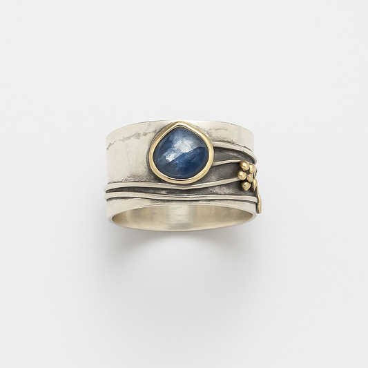 Silver ring with a blue sapphire gemstone, featuring a unique layered design and gold accents, perfect for elegant jewelry collections.