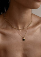 Gold layered necklaces with a black pendant on a woman's neck, showcasing elegant jewelry fashion. Perfect for style and accessory enthusiasts.