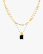 Gold layered chain necklace with a black rectangular pendant, featuring a sleek design. Perfect for fashion-forward jewelry enthusiasts.