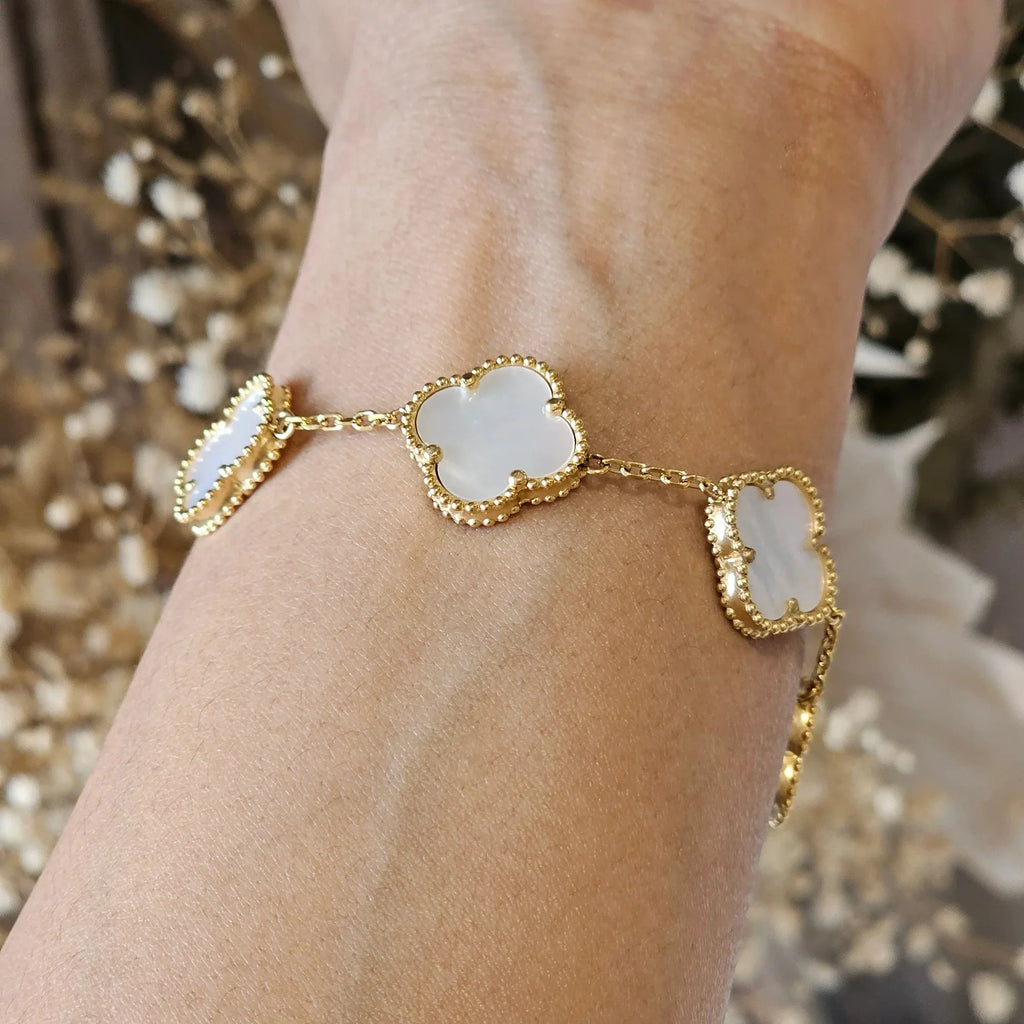 Gold bracelet with mother-of-pearl clover charms on wrist, elegant jewelry, luxury fashion accessory, delicate design, stylish wristwear.
