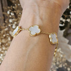 Gold bracelet with mother-of-pearl clover charms on wrist, elegant jewelry, luxury fashion accessory, delicate design, stylish wristwear.