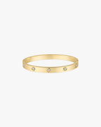Gold bangle bracelet with embedded round diamonds on a white background. Elegant jewelry accessory, luxury fashion statement piece.