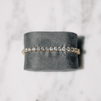 Elegant diamond tennis bracelet on gray velvet, featuring sparkling round-cut diamonds set in gold, perfect for luxury jewelry enthusiasts.