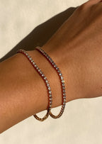 Elegant gold tennis bracelet with sparkling diamonds on wrist, luxury jewelry, fashion accessory, close-up, sunlight.