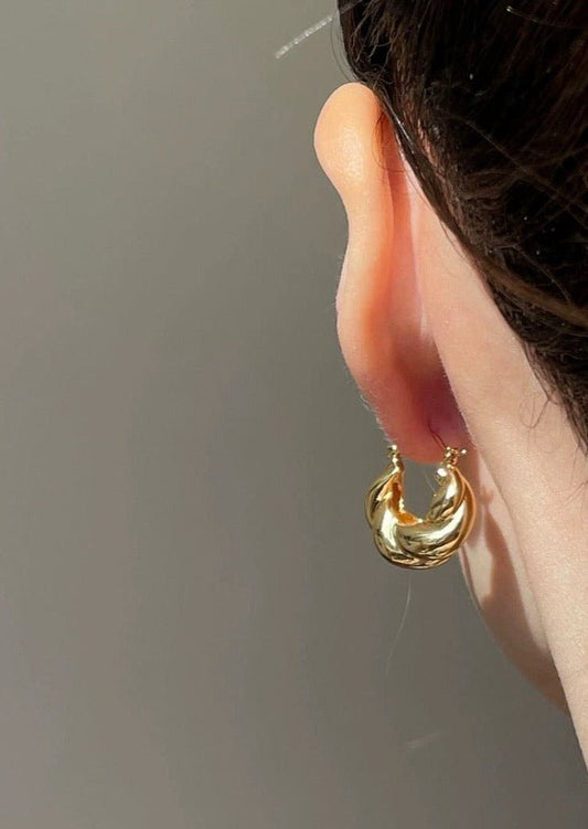 Gold hoop earring on woman's ear, close-up. Elegant jewelry, shiny finish, fashion accessory, minimalist style, perfect for everyday wear.