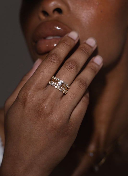 Close-up of a woman's hand with glossy lips, showcasing elegant gold and diamond stacked rings on her fingers, highlighting luxury jewelry fashion.