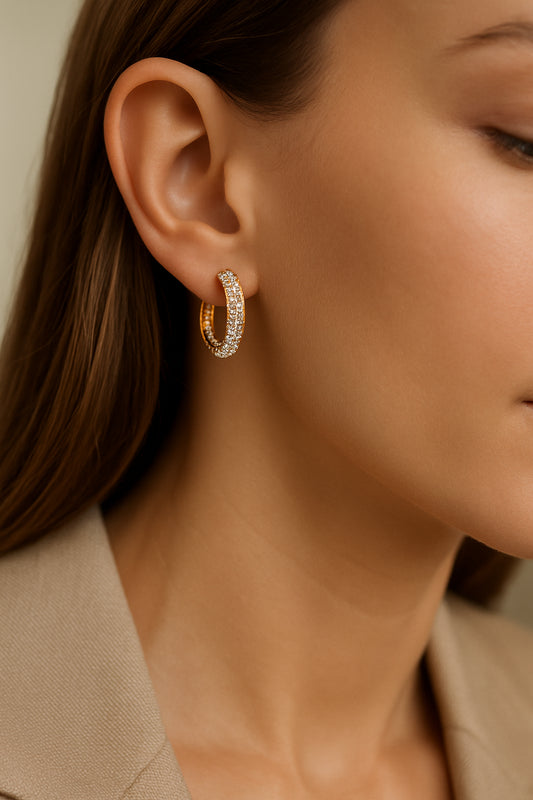 Close-up of a woman's ear wearing a gold hoop earring encrusted with diamonds, showcasing elegant jewelry fashion and luxury accessories.