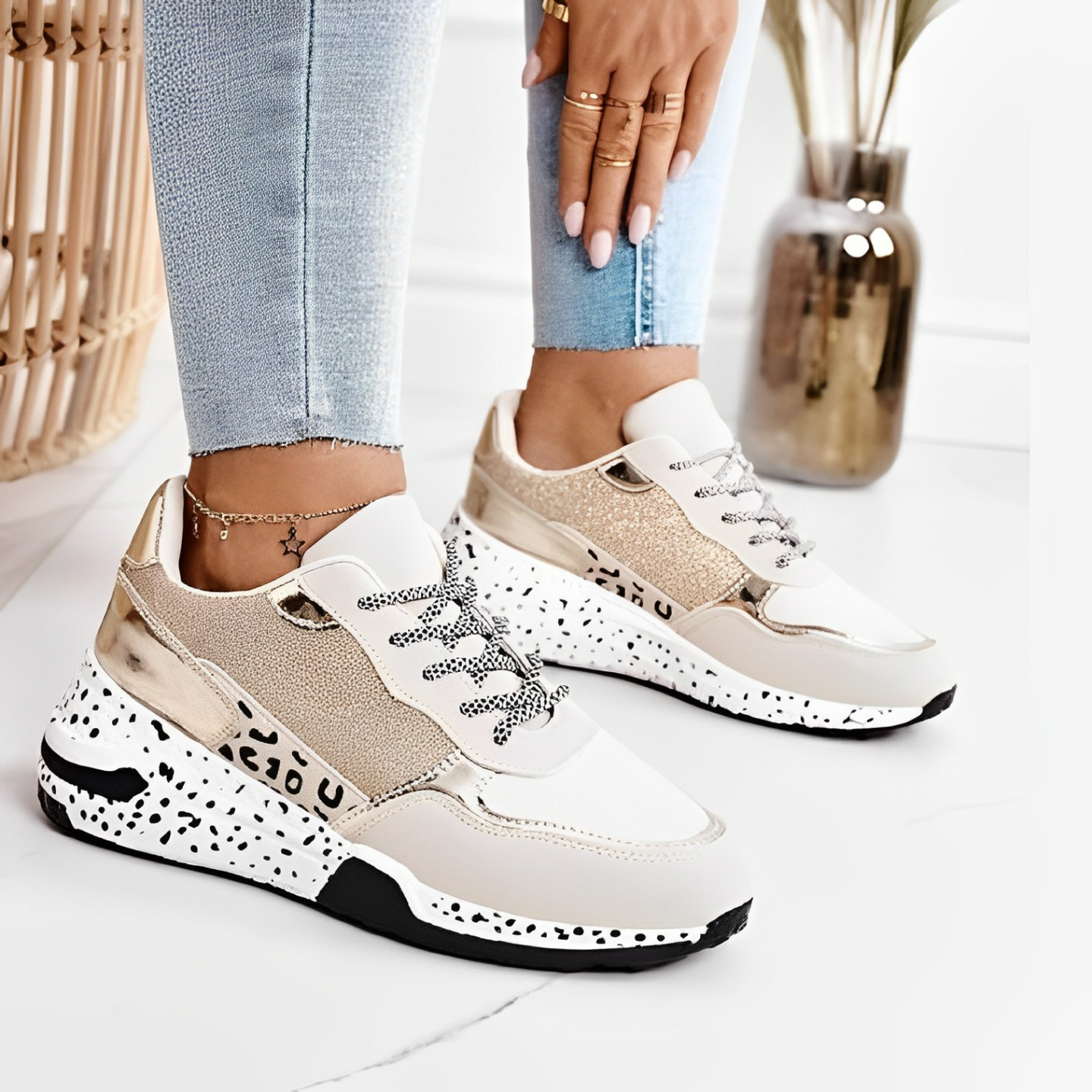White and beige sneakers with black speckles worn by a person on a light background
