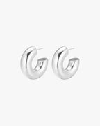 Silver hoop earrings on white background, minimalist design, polished finish, women's fashion jewelry, modern accessories, elegant style.
