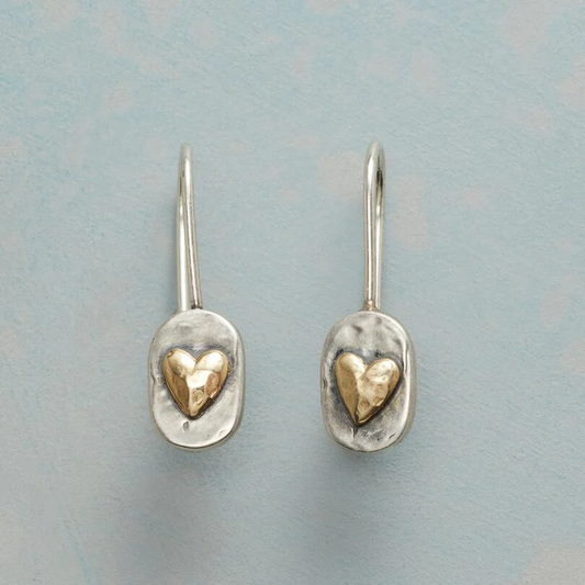 Pair of silver earrings with gold hearts on a light blue background