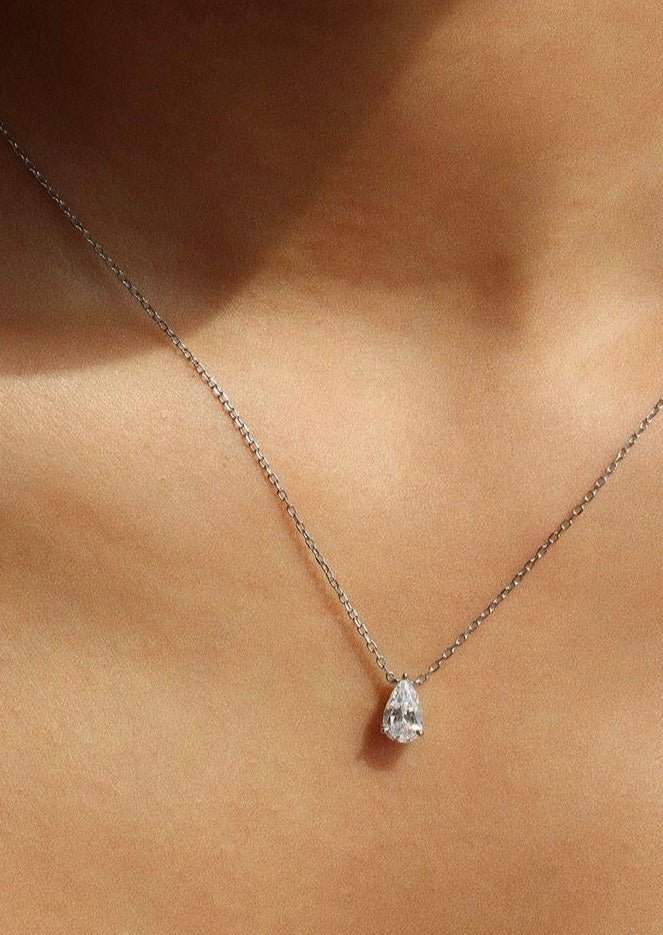 Elegant teardrop diamond necklace on delicate silver chain, showcased on skin. Perfect for luxury jewelry, fashion accessory, and diamond pendant keywords.