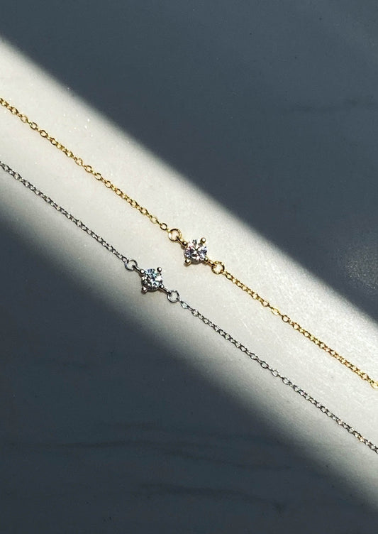 Two delicate gold and silver chain bracelets with sparkling star-shaped pendants, elegantly displayed on a soft gray background.