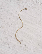 Gold chain bracelet on textured concrete background, minimalist jewelry, elegant accessory, fashion statement, simple design, luxury style.