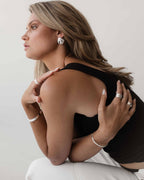 Woman wearing silver jewelry, including earrings, rings, and bracelets, in a stylish pose. Fashion accessories, elegant design, modern style.
