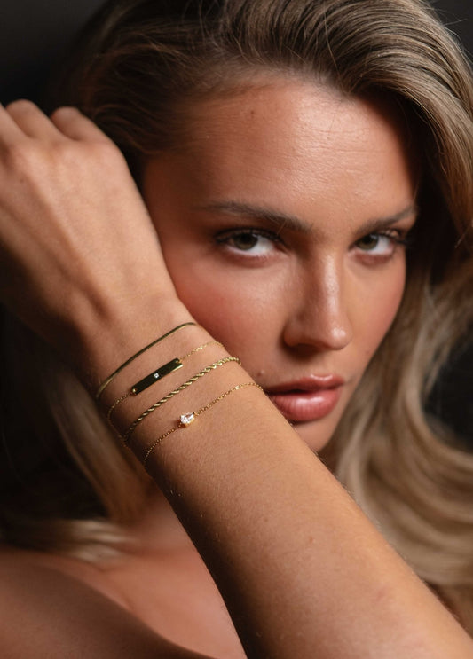 Woman showcasing elegant gold bracelets and a diamond bracelet on her wrist, highlighting luxury jewelry fashion and style.