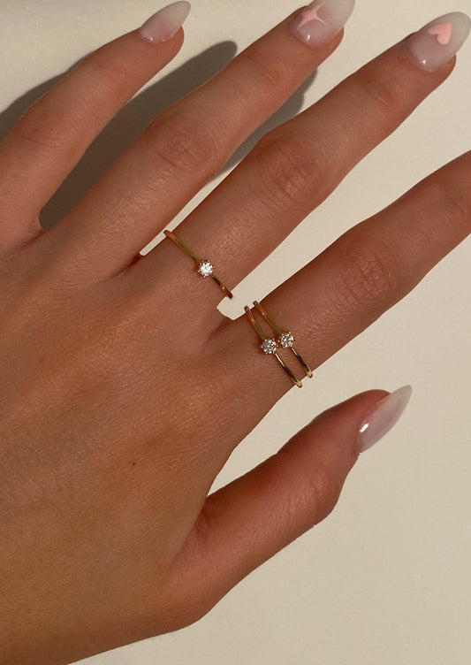 Elegant hand wearing minimalist gold rings with small diamonds, showcasing trendy nail art. Perfect for jewelry fashion and manicure inspiration.