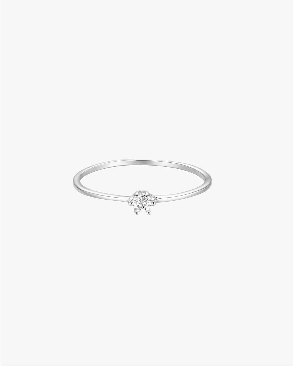 Minimalist silver ring with a single round diamond on a thin band, set against a white background. Elegant jewelry, perfect for engagements or gifts.