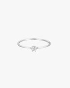 Minimalist silver ring with a single round diamond on a thin band, set against a white background. Elegant jewelry, perfect for engagements or gifts.