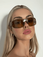 Woman wearing brown sunglasses against a plain background