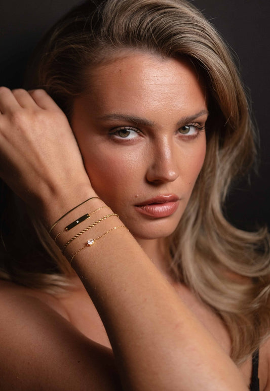Woman wearing elegant gold bracelets, showcasing minimalist jewelry fashion. Close-up portrait with focus on accessories and natural beauty.