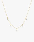 Gold necklace with five dangling diamond pendants on a delicate chain, elegant jewelry, minimalist design, perfect for special occasions.
